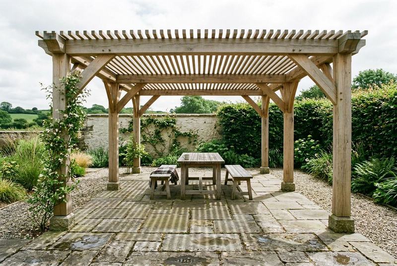 Timber pergola with slatted roof over a stone patio in a garden