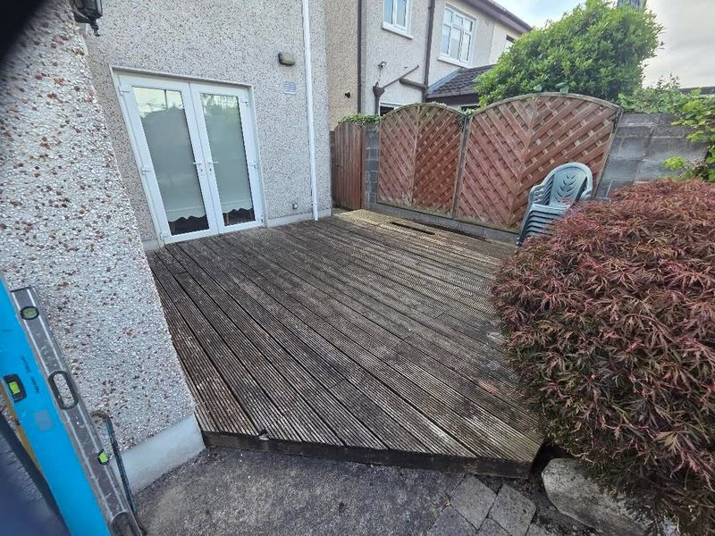 A weathered grooved timber deck outside patio doors, greyed and worn, before it was taken up and replaced